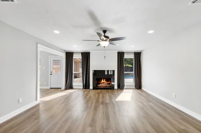 a view of a livingroom with a fireplace a ceiling fan and a window