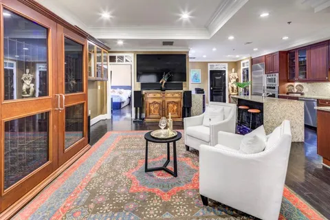 a living room with furniture a flat screen tv and kitchen view