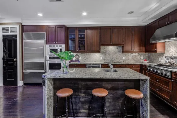 a kitchen with stainless steel appliances granite countertop a sink a stove and wooden cabinets