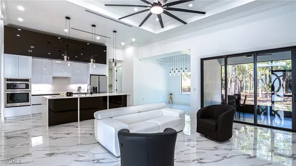 a living room with stainless steel appliances kitchen island granite countertop furniture a rug and white walls