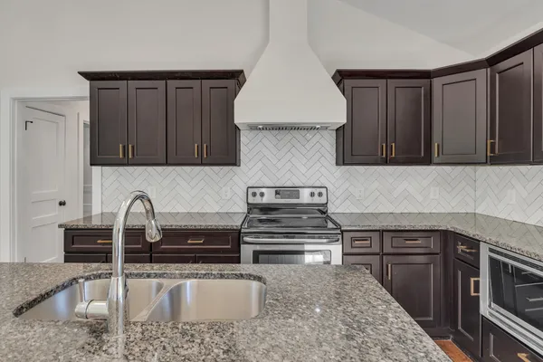 a kitchen with sink a stove and cabinets