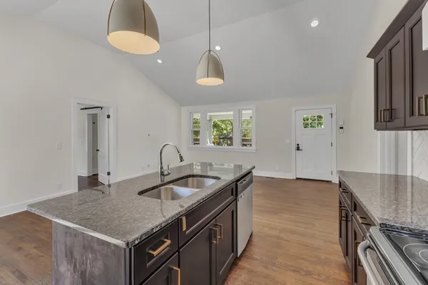 a kitchen with stainless steel appliances granite countertop a sink a stove and a wooden floors