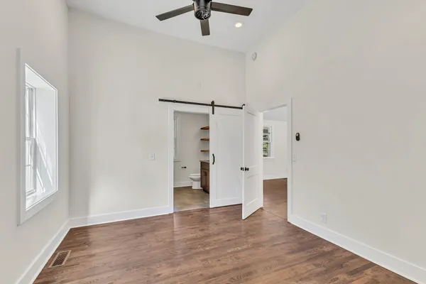a view of an empty room with a window and wooden floor