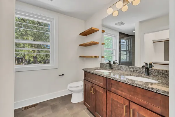 a bathroom with a granite countertop sink a large mirror and a window