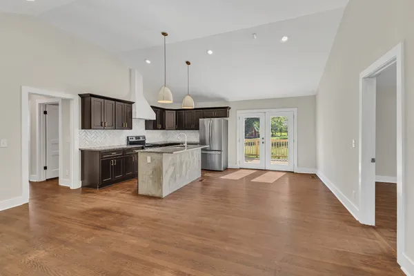 a large kitchen with stainless steel appliances granite countertop a stove a sink dishwasher a microwave oven and white cabinets with wooden floor