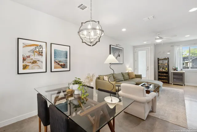 a living room with furniture a dining table and paintings on the wall