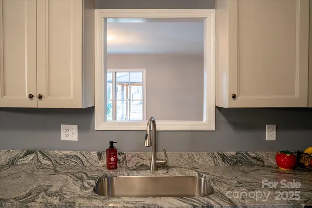a kitchen with granite countertop white cabinets and a sink