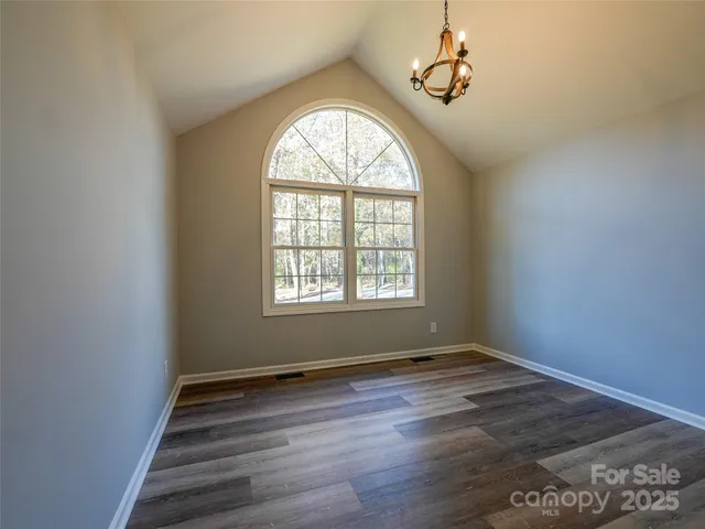 an empty room with wooden floor windows and fan