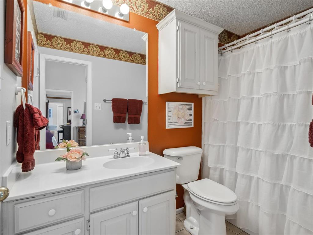 299 Lamplight Path Holly Lake Ranch, TX 75765 - Photo 23 of 40 a bathroom with a sink a toilet and shower curtain