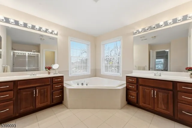 a spacious bathroom with a tub a double vanity sink and a large mirror of cabinet