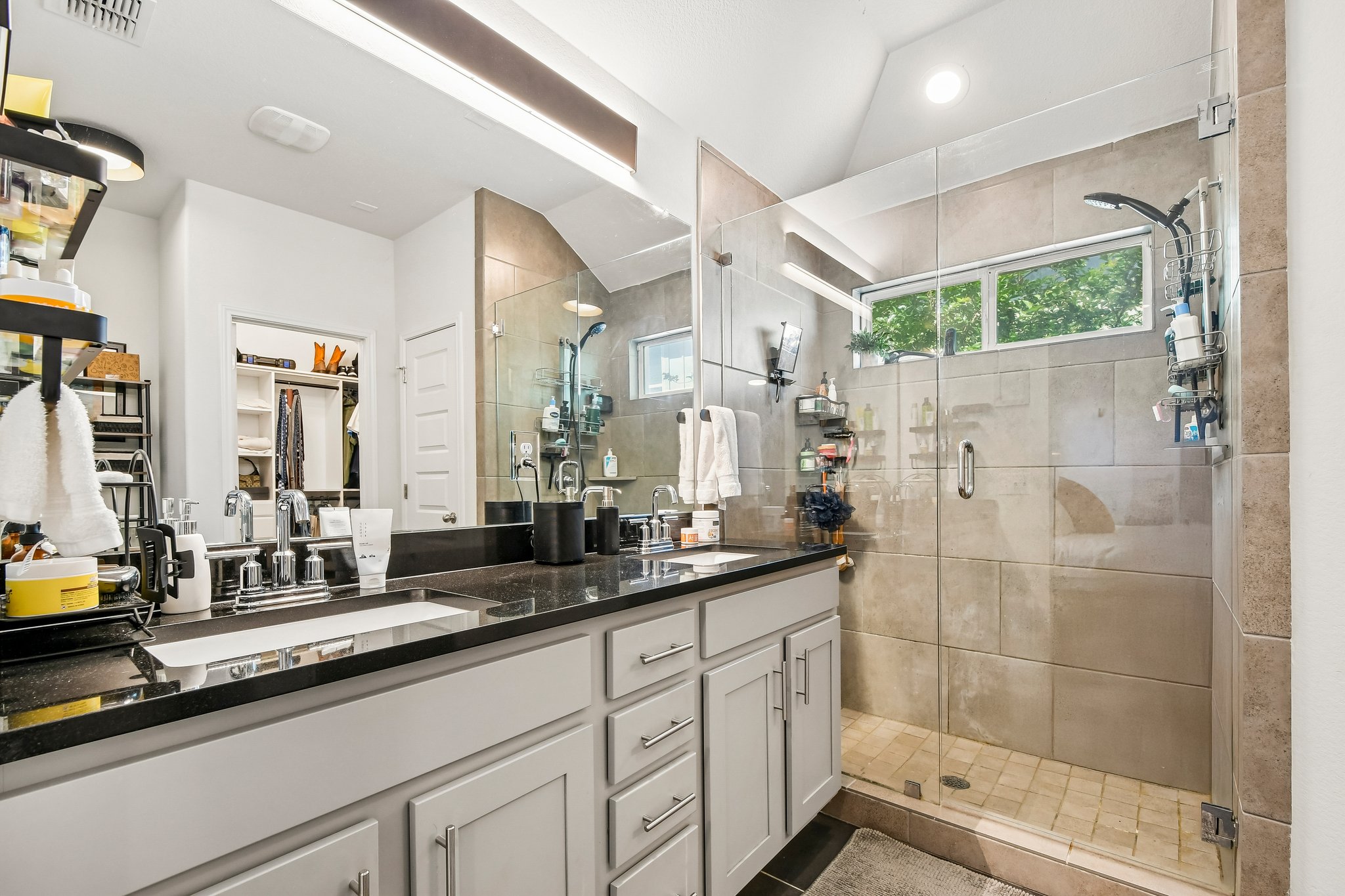 10700 Sentinel Drive Austin, TX 78747 - Photo 17 of 27 The primary ensuite keeps it simple and sharp with dual sinks, a glass walk-in shower, and a striking granite vanity.