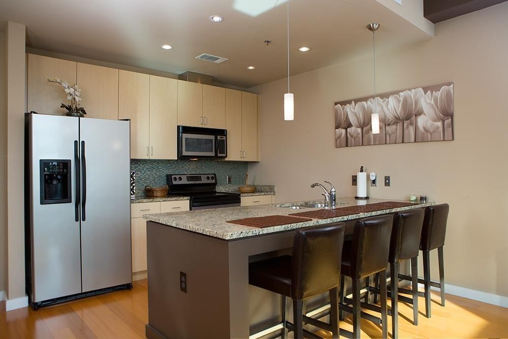 a kitchen with a sink a microwave a refrigerator and chairs