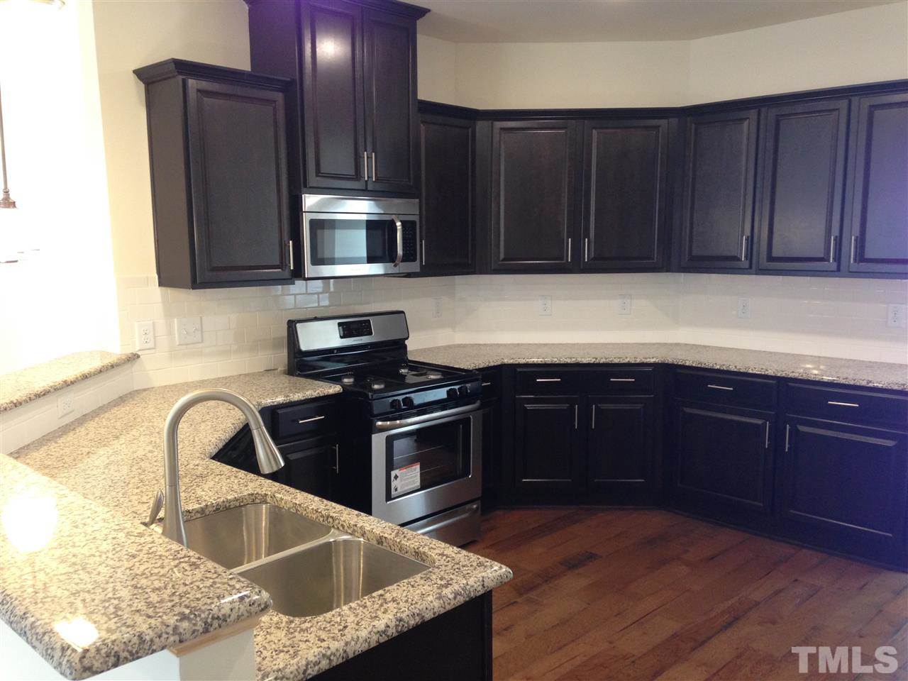 632 Edgewater Ridge Court Apex, NC 27523 - Photo 4 of 21 a kitchen with granite countertop stainless steel appliances a sink and a stove