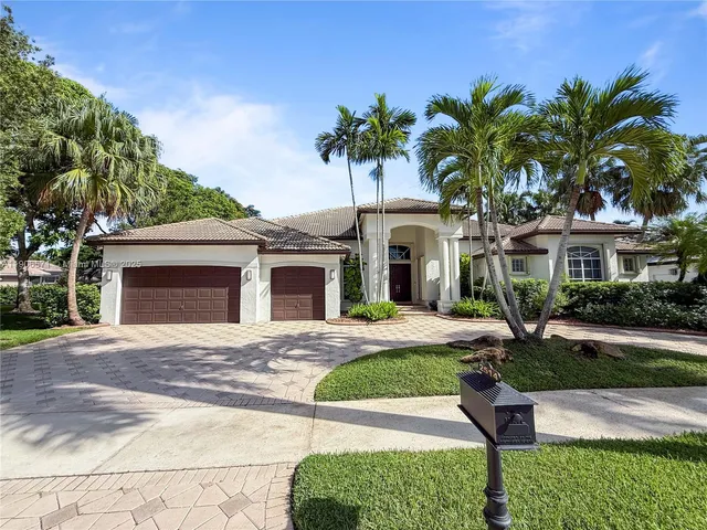 a front view of a house with a garden and palm trees