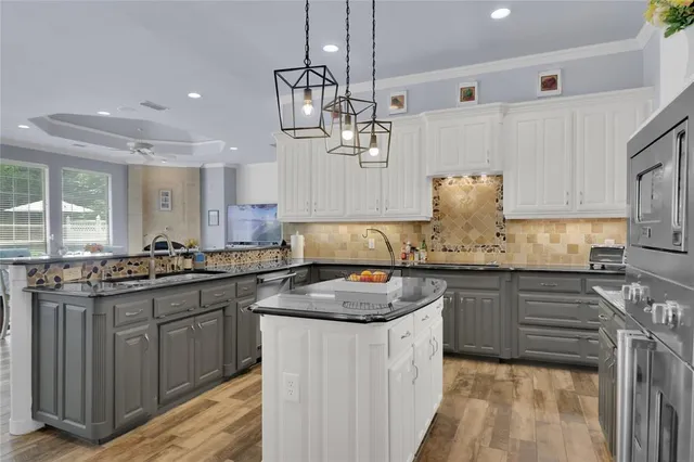 a kitchen with kitchen island granite countertop a sink stove cabinets and wooden floor