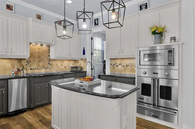 a kitchen with stainless steel appliances granite countertop a sink a stove and cabinets