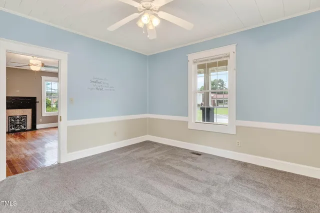 an empty room with windows and chandelier fan