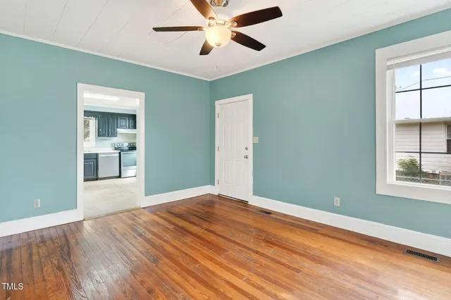 a view of empty room with wooden floor and fan