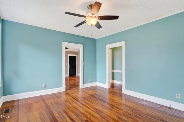 a view of an empty room with window and wooden floor