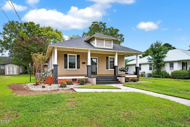 a front view of a house with garden and trees