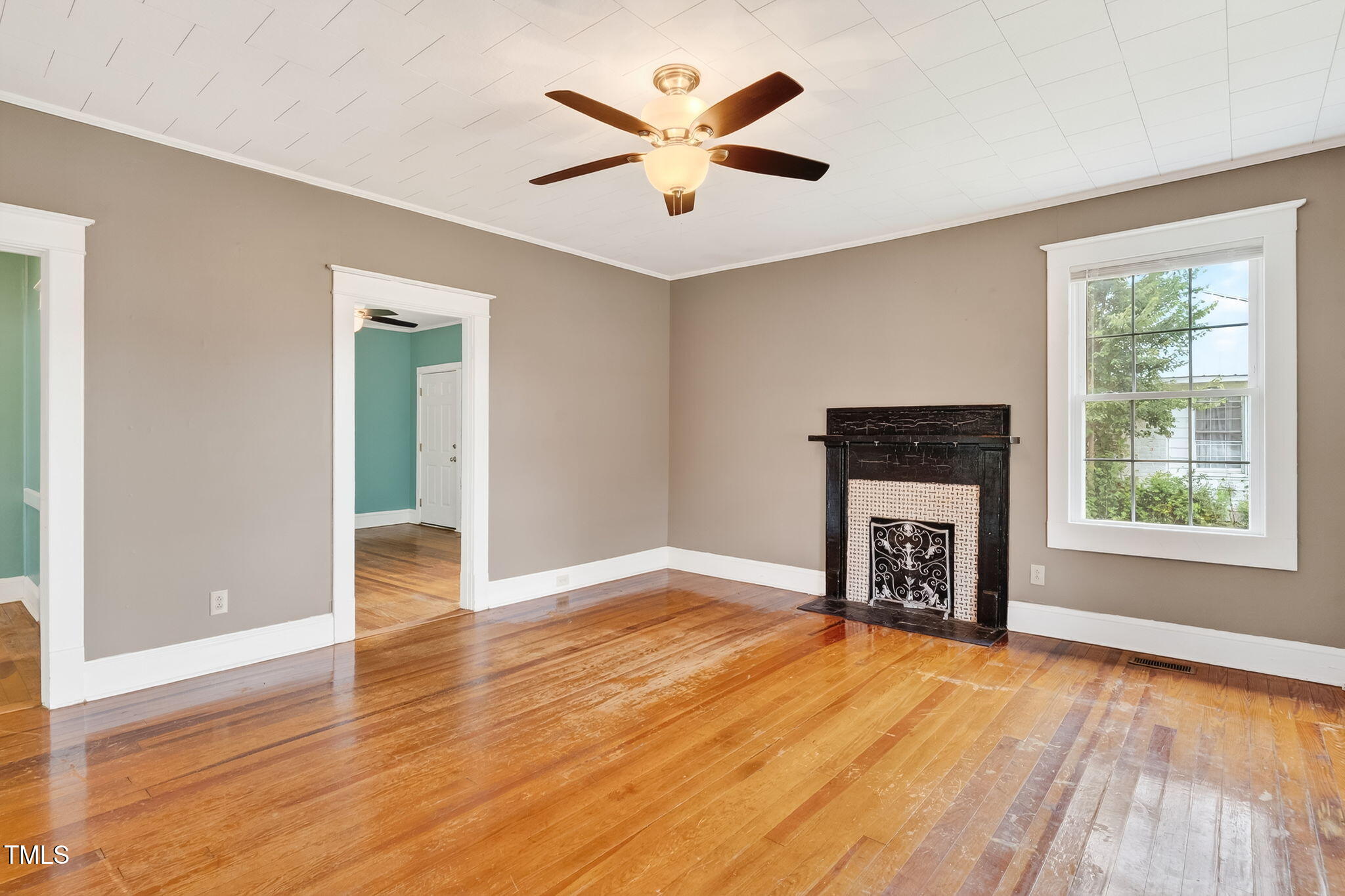 108 West C Street Erwin, NC 28339 - Photo 7 of 37 an empty room with windows a fireplace a ceiling fan and wooden floor