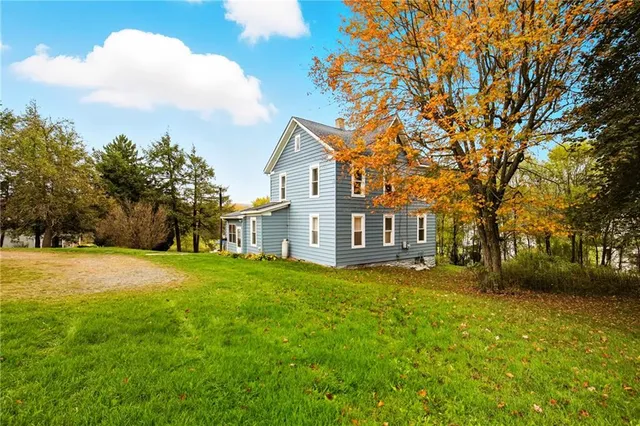 a view of a big house with a big yard and large trees