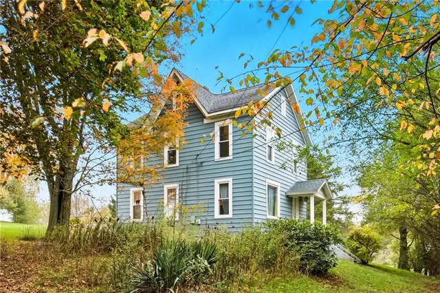 a front view of a house with a tree