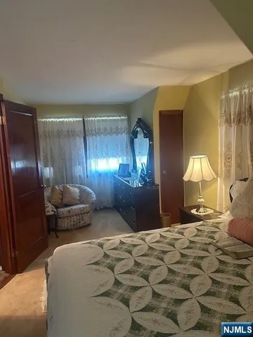 a bedroom with a bed large mirror and lamp