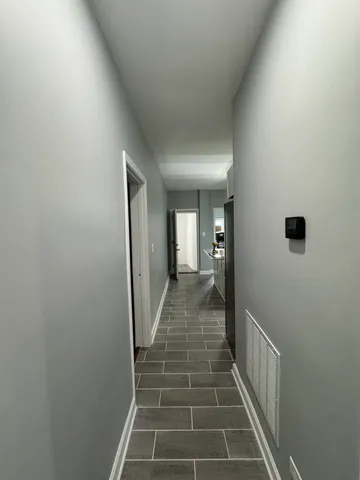 a view of a hallway with wooden floor and a bathroom