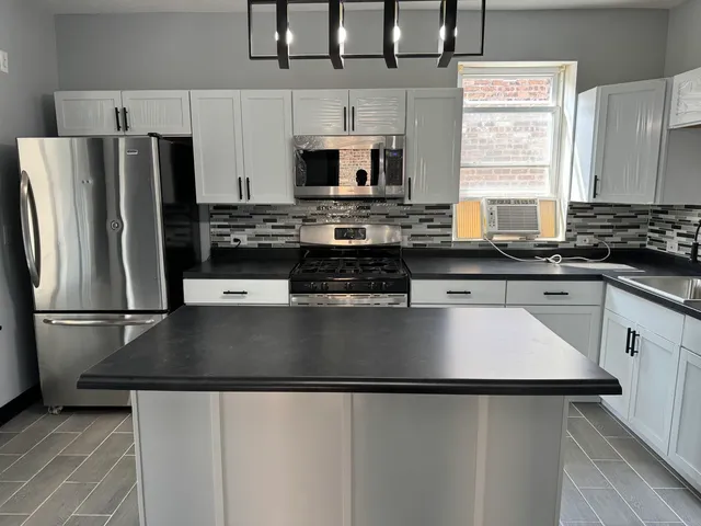 a kitchen with stainless steel appliances granite countertop a refrigerator a stove a sink and a microwave