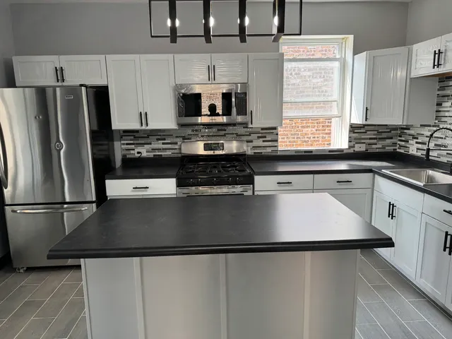 a kitchen with granite countertop a refrigerator stove and microwave