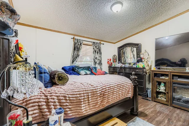 a bedroom with a bed a dresser and potted plants with the wooden floor