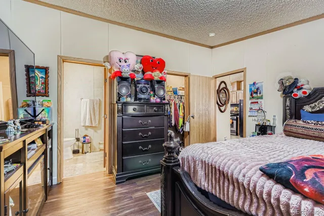 a bedroom with a bed dresser and wooden floor