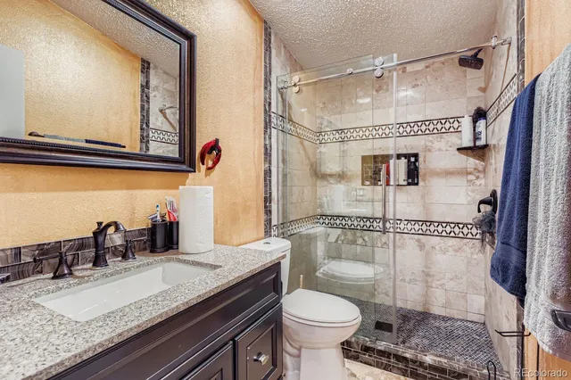 a bathroom with a granite countertop sink toilet a mirror and shower