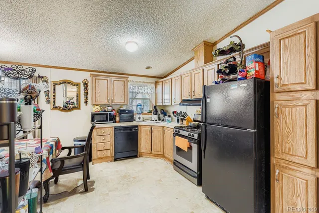 a kitchen with granite countertop a refrigerator and a stove top oven