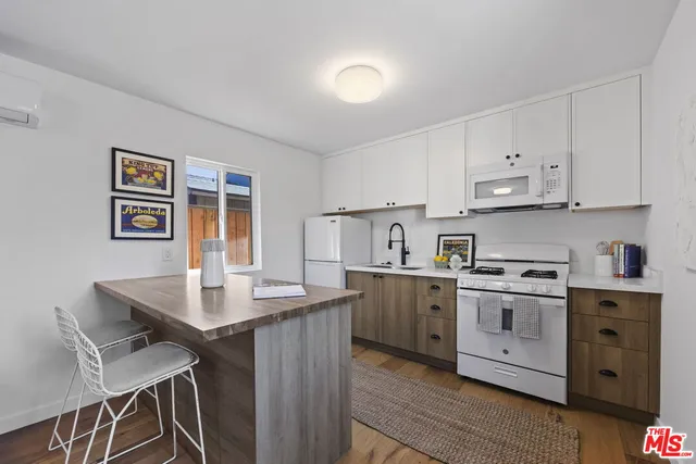 a kitchen with stainless steel appliances granite countertop a stove top oven a sink dishwasher and a refrigerator with wooden floor