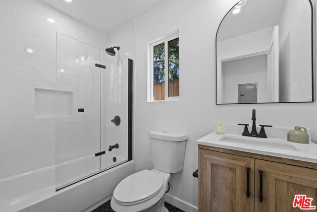 a bathroom with a toilet a sink a mirror a bathtub and shower