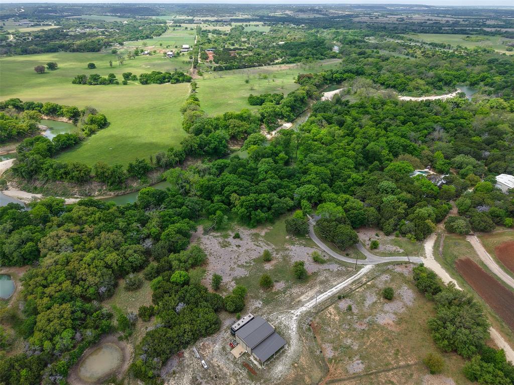 377 County Road 2530 Meridian, TX 76665 - Photo 25 of 25 a view of a lush green forest with lawn chairs and large trees