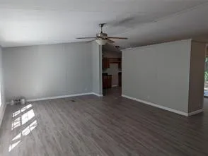 a view of empty room with wooden floor and ceiling fan