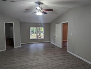 12186 Hairston Circle Willis, TX 77318 - Photo 3 of 16 an empty room with wooden floor chandelier fan and windows
