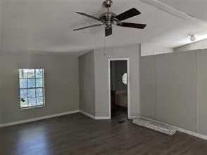an empty room with wooden floor chandelier fan and windows