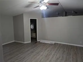 an empty room with wooden floor closet and windows