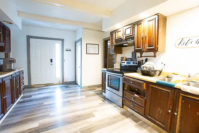 a kitchen with stainless steel appliances granite countertop a stove top oven a sink dishwasher and a refrigerator with wooden floor