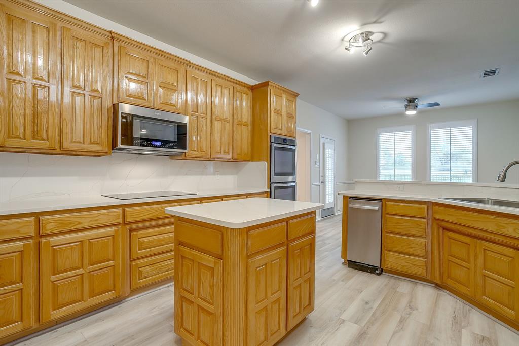 125 View Point Court Aledo, TX 76008 - Photo 12 of 34 a kitchen with stainless steel appliances granite countertop a stove a sink dishwasher and a microwave oven with wooden cabinets