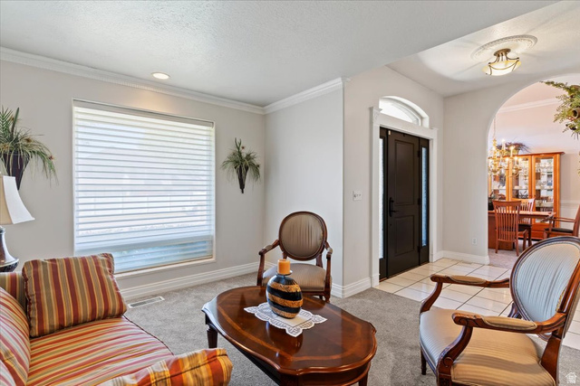 1924 North 2000th Street East Layton, UT 84040 - Photo 7 of 41 Living area with arched walkways, light colored carpet, crown molding, light tile patterned floors, and a textured ceiling