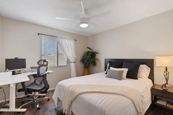 a bedroom with a bed a desk and chair with wooden floor