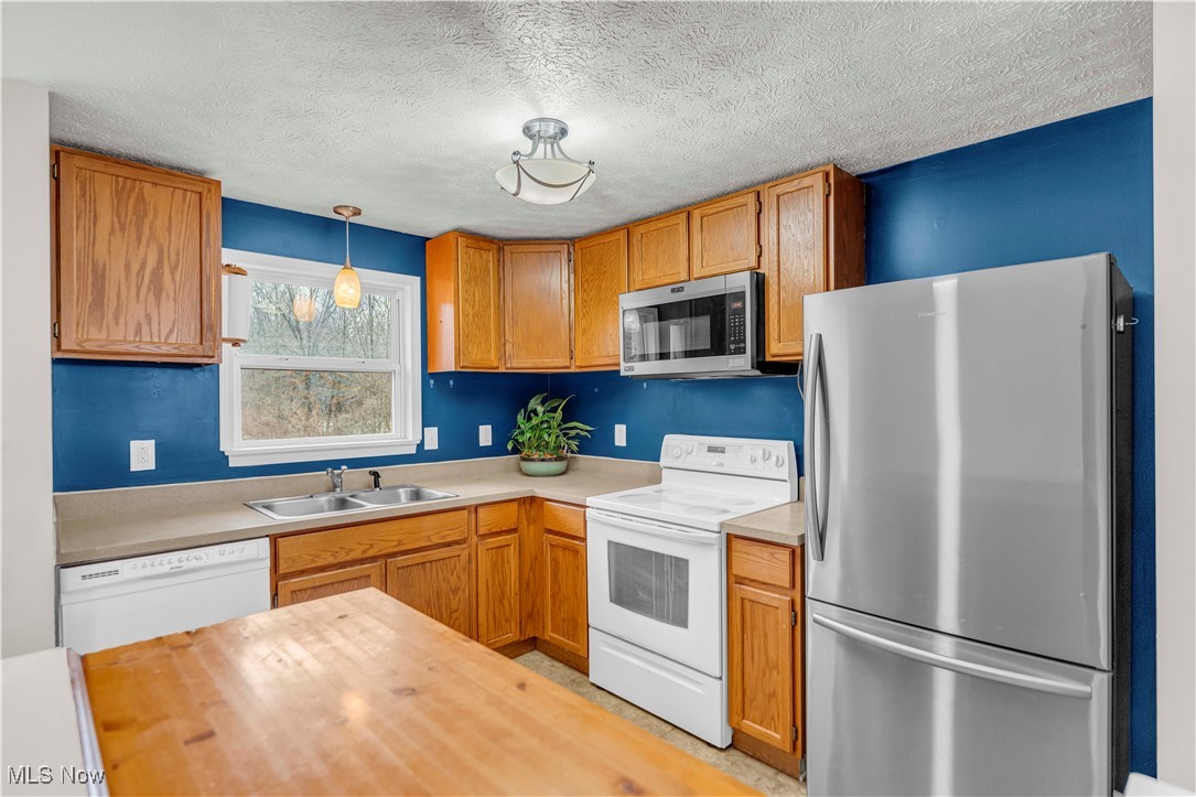 8110 Risden Road Vermilion, OH 44089 - Photo 7 of 48 Kitchen featuring stainless steel appliances, sink, pendant lighting, and a textured ceiling
