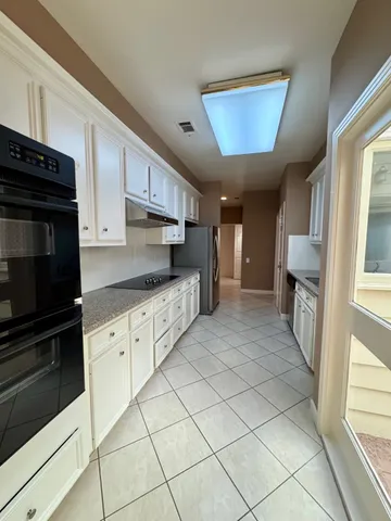 a kitchen with granite countertop a refrigerator stove top oven and sink