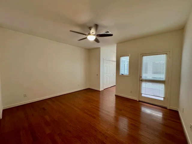 a view of an empty room with a window and wooden floor