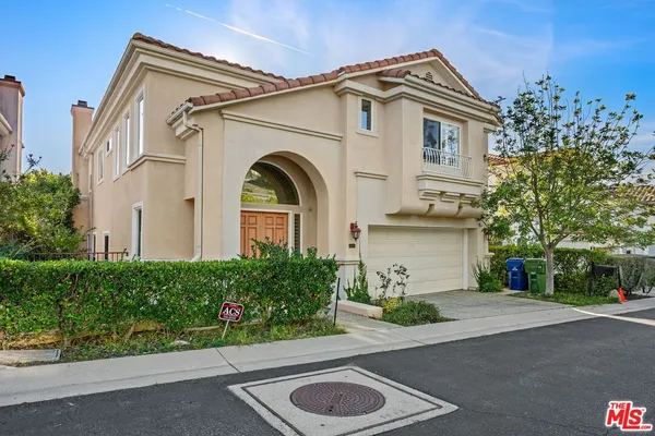 a view of a white house with a street and potted plants